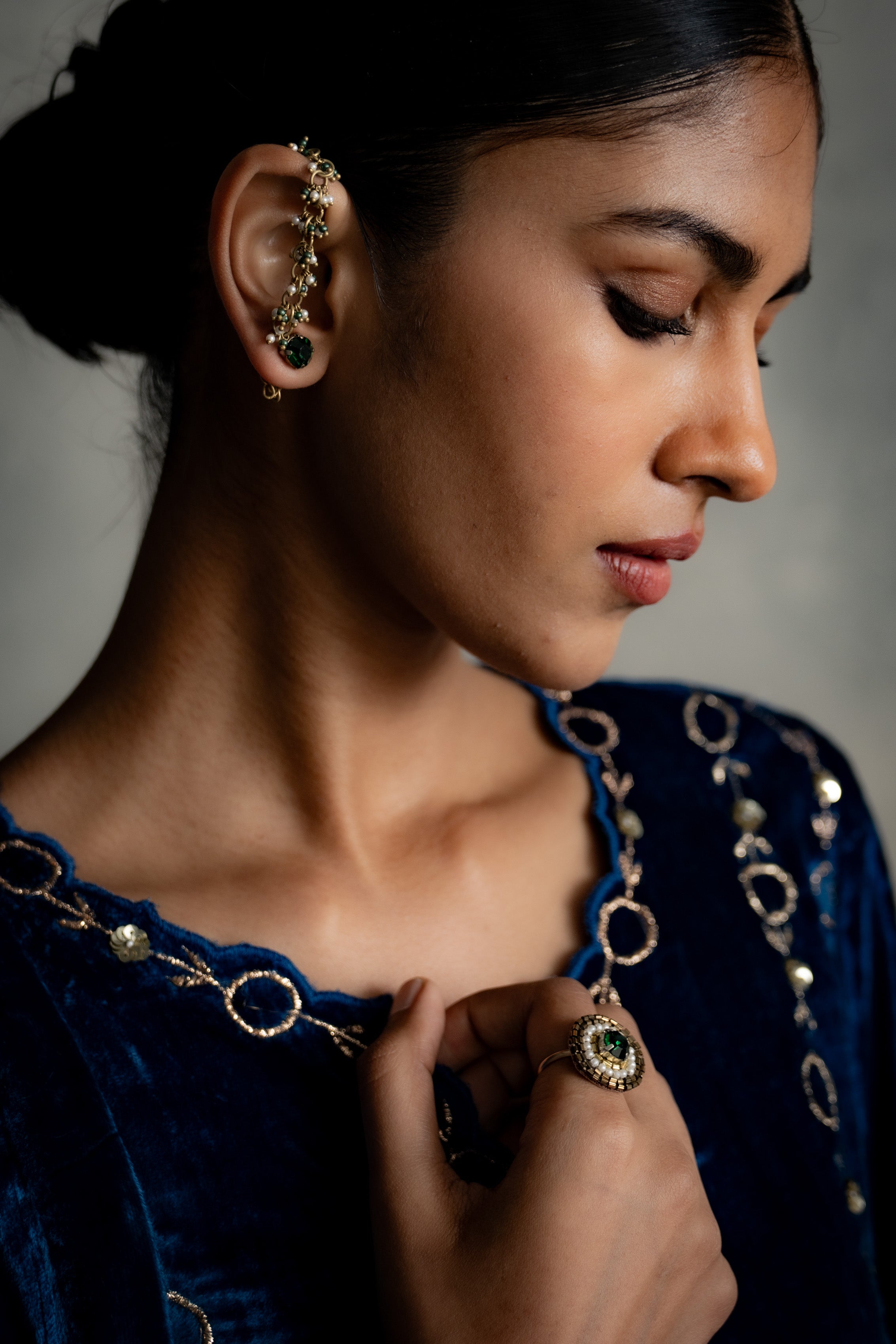 Woman wearing gold earrings and a necklace with a dark background
